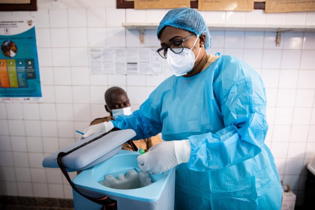 Mimi Henriette Mishika lấy lọ vắc-xin khỏi thùng bảo quan lạnh để bắt đầu những mũi tiêm chủng đầu tiên trong ngày tại phòng khám Ngaliema, Kinshasa. Ảnh: Lisa Murray.